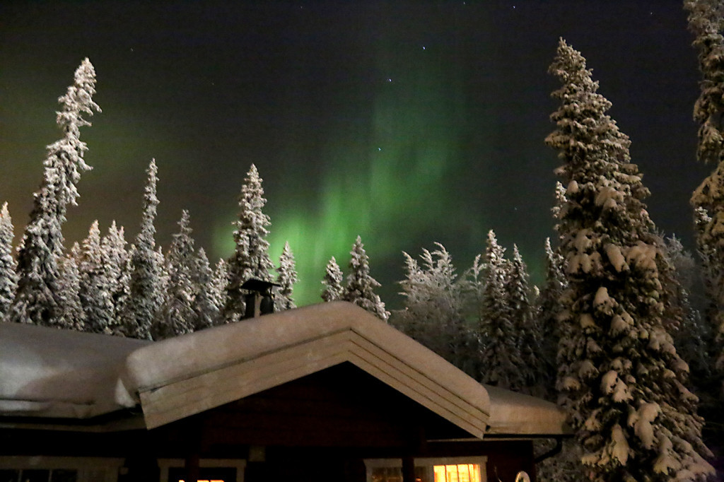 Finnland: Nordlichter aurora-borealis über einer Hütte imWald